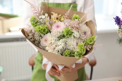 Photo of Florist with beautiful bouquet of flowers indoors, closeup