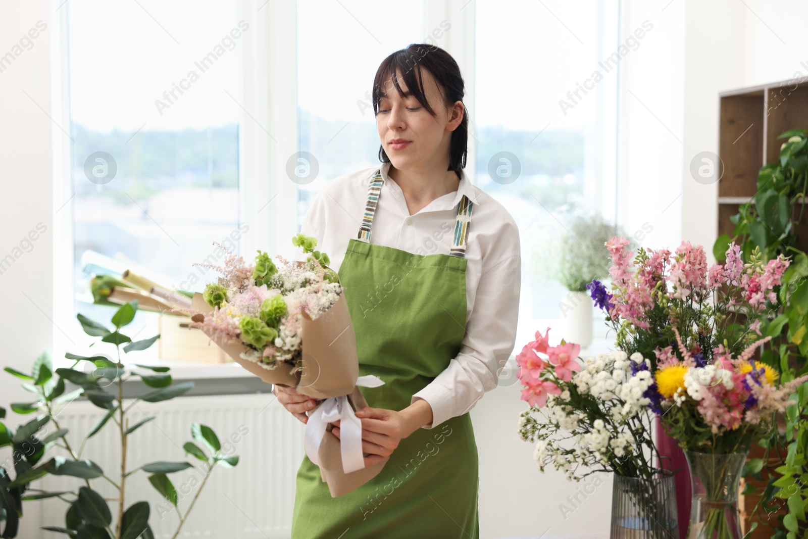 Florist with beautiful bouquet of flowers indoors Photo of Florist with beautiful bouquet of flowers indoors