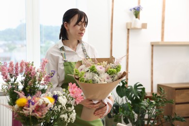 Photo of Florist with beautiful bouquet of flowers indoors