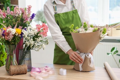 Photo of Florist with beautiful bouquet of flowers indoors, closeup