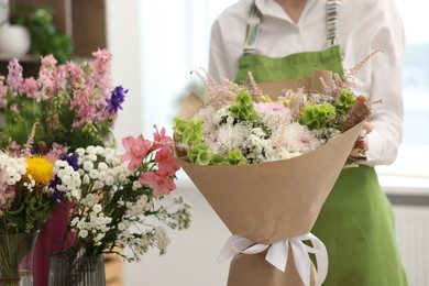 Photo of Florist with beautiful bouquet of flowers indoors, closeup