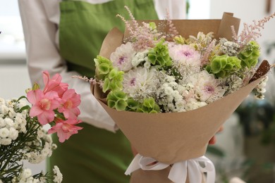 Photo of Florist with beautiful bouquet of flowers indoors, closeup
