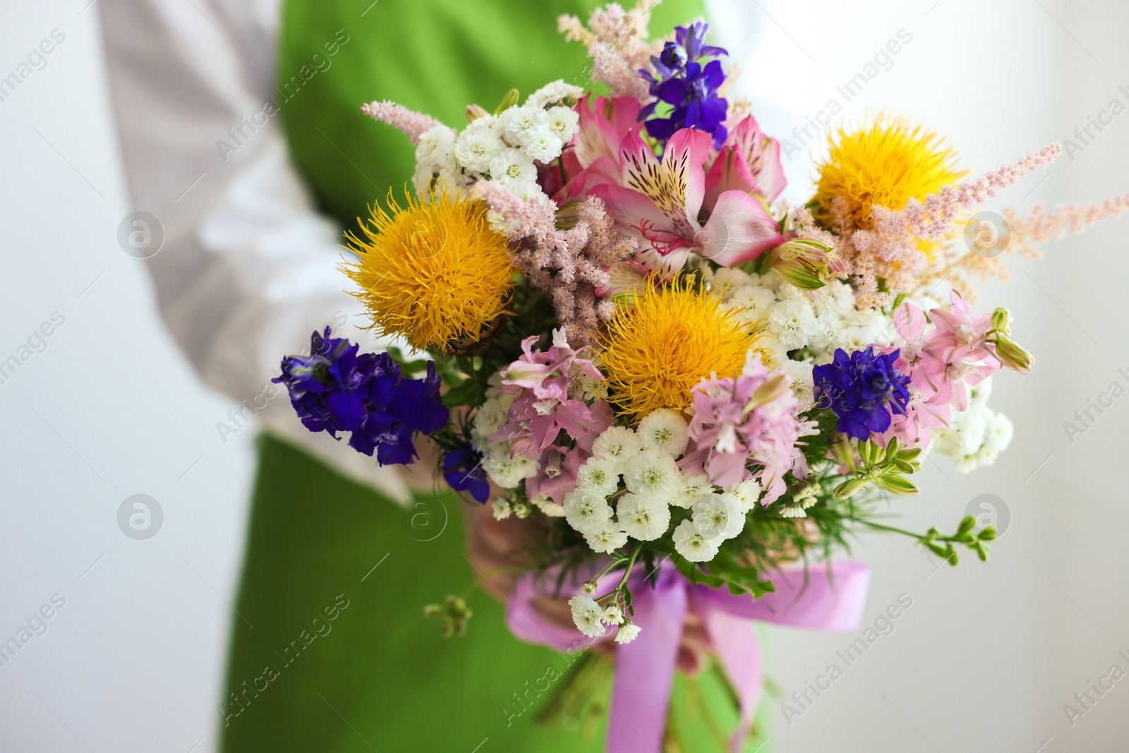 Florist with beautiful bouquet of flowers near white wall indoors, closeup Photo of Florist with beautiful bouquet of flowers near white wall indoors, closeup