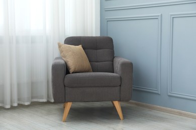 Photo of Comfortable armchair near light blue wall indoors
