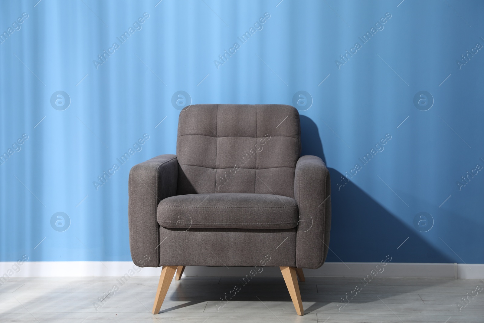 Comfortable grey armchair near blue wall indoors Photo of Comfortable grey armchair near blue wall indoors