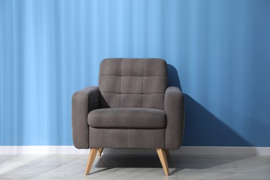 Photo of Comfortable grey armchair near blue wall indoors