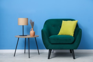 Photo of Comfortable armchair and decor near blue wall indoors