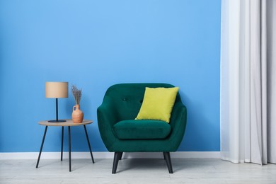 Photo of Comfortable armchair and decor near blue wall indoors