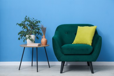 Photo of Comfortable armchair and decor near blue wall indoors