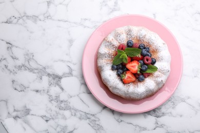 Photo of Tasty Bundt cake with powdered sugar and berries on white marble table, top view. Space for text
