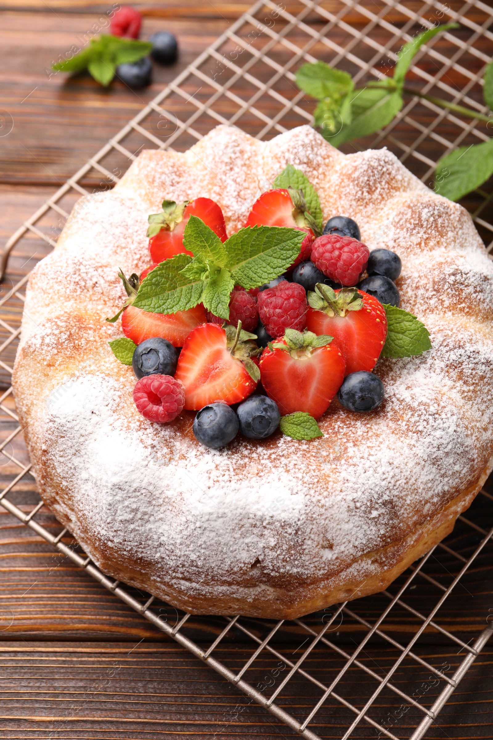 Tasty Bundt cake with powdered sugar and berries on wooden table, closeup Photo of Tasty Bundt cake with powdered sugar and berries on wooden table, closeup