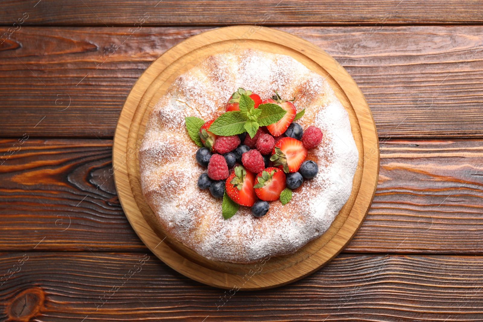Tasty Bundt cake with powdered sugar and berries on wooden table, top view Photo of Tasty Bundt cake with powdered sugar and berries on wooden table, top view