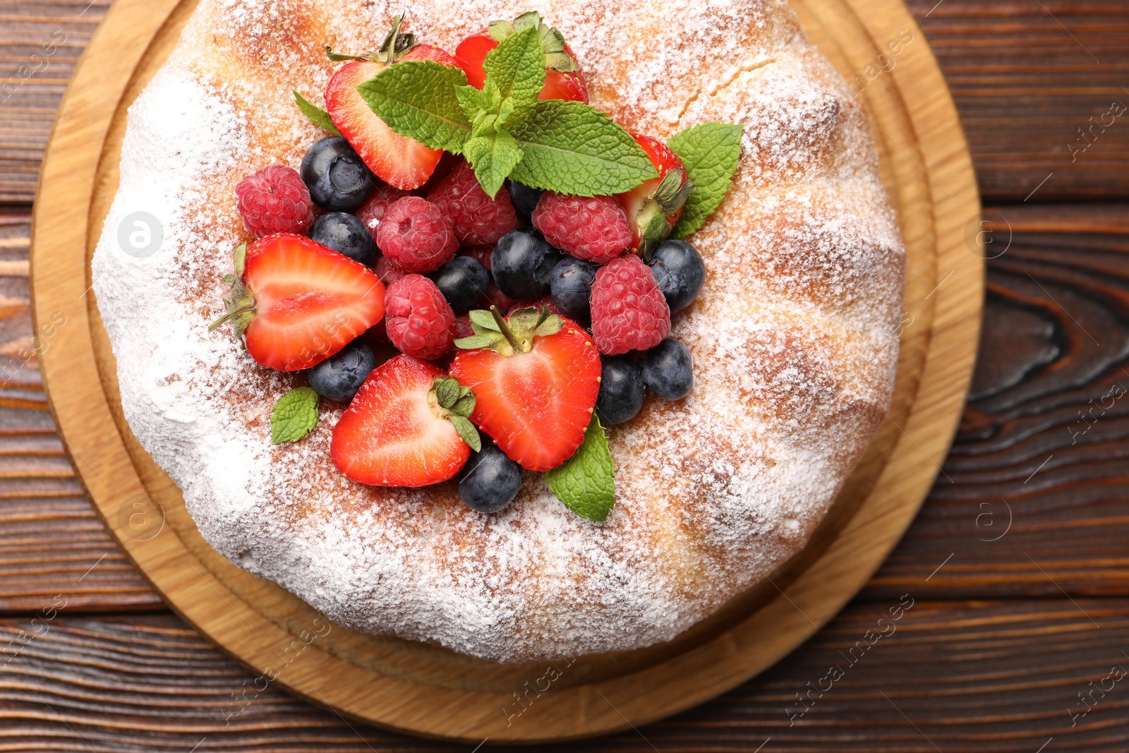 Tasty Bundt cake with powdered sugar and berries on wooden table, top view Photo of Tasty Bundt cake with powdered sugar and berries on wooden table, top view