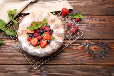 Photo of Tasty Bundt cake with powdered sugar and berries on wooden table, flat lay. Space for text