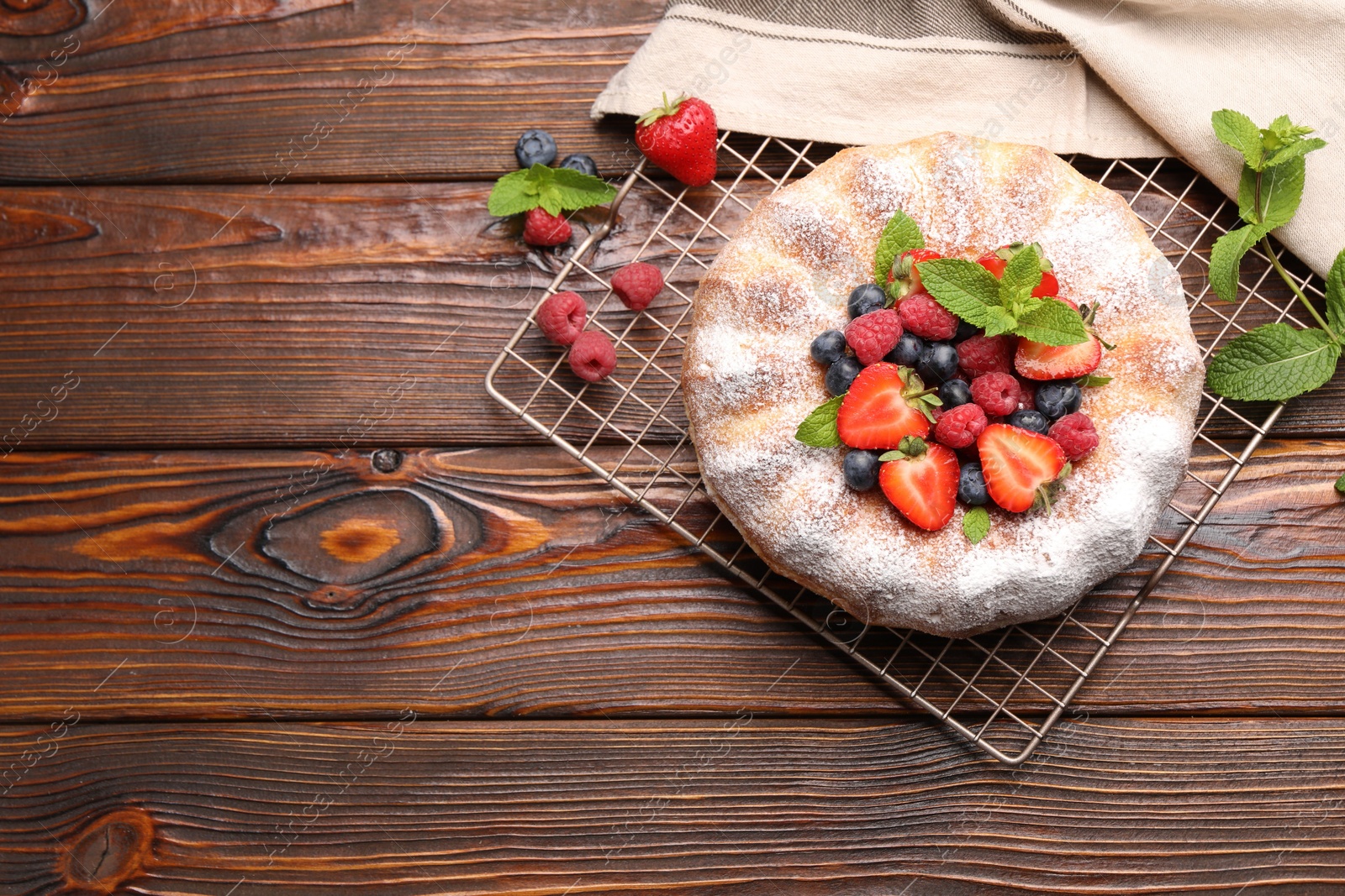 Tasty Bundt cake with powdered sugar and berries on wooden table, flat lay. Space for text Photo of Tasty Bundt cake with powdered sugar and berries on wooden table, flat lay. Space for text