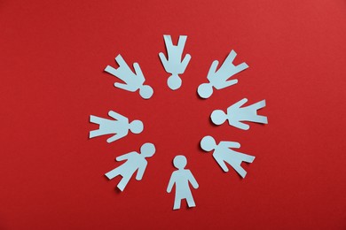 Photo of Human paper figures on red background, flat lay