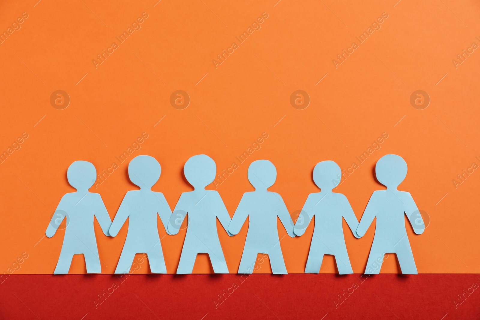 Photo of Human paper figures holding hands on color background, flat lay. Space for text