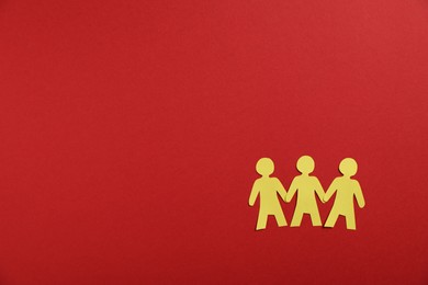 Photo of Human paper figures holding hands on red background, flat lay. Space for text