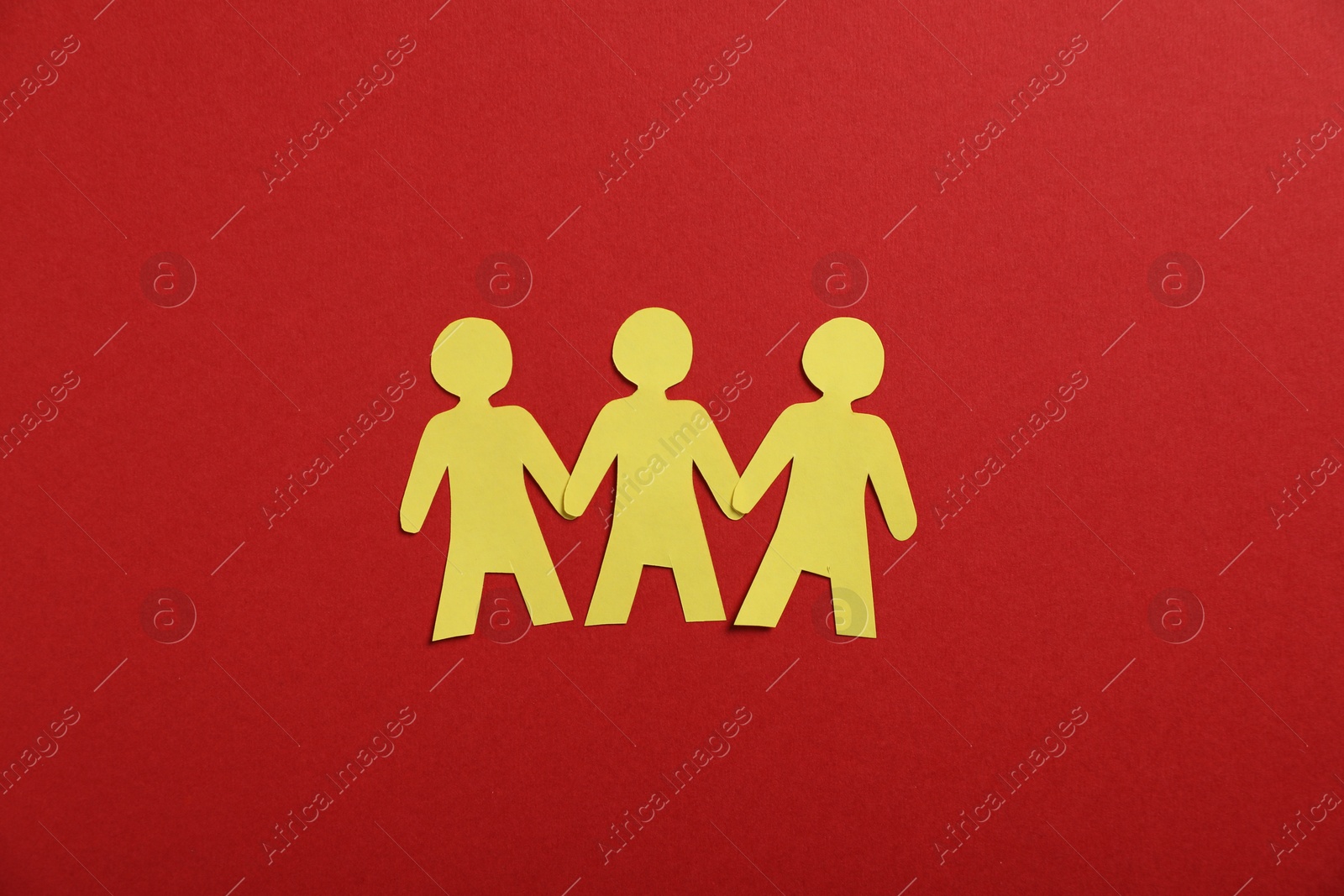 Photo of Human paper figures holding hands on red background, flat lay
