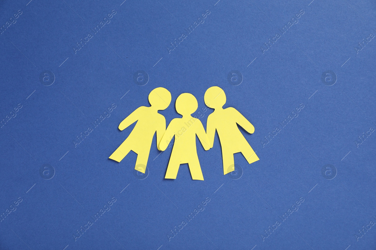 Photo of Human paper figures holding hands on blue background, flat lay