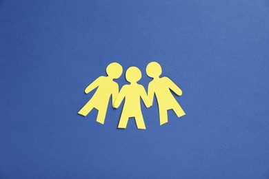 Photo of Human paper figures holding hands on blue background, flat lay