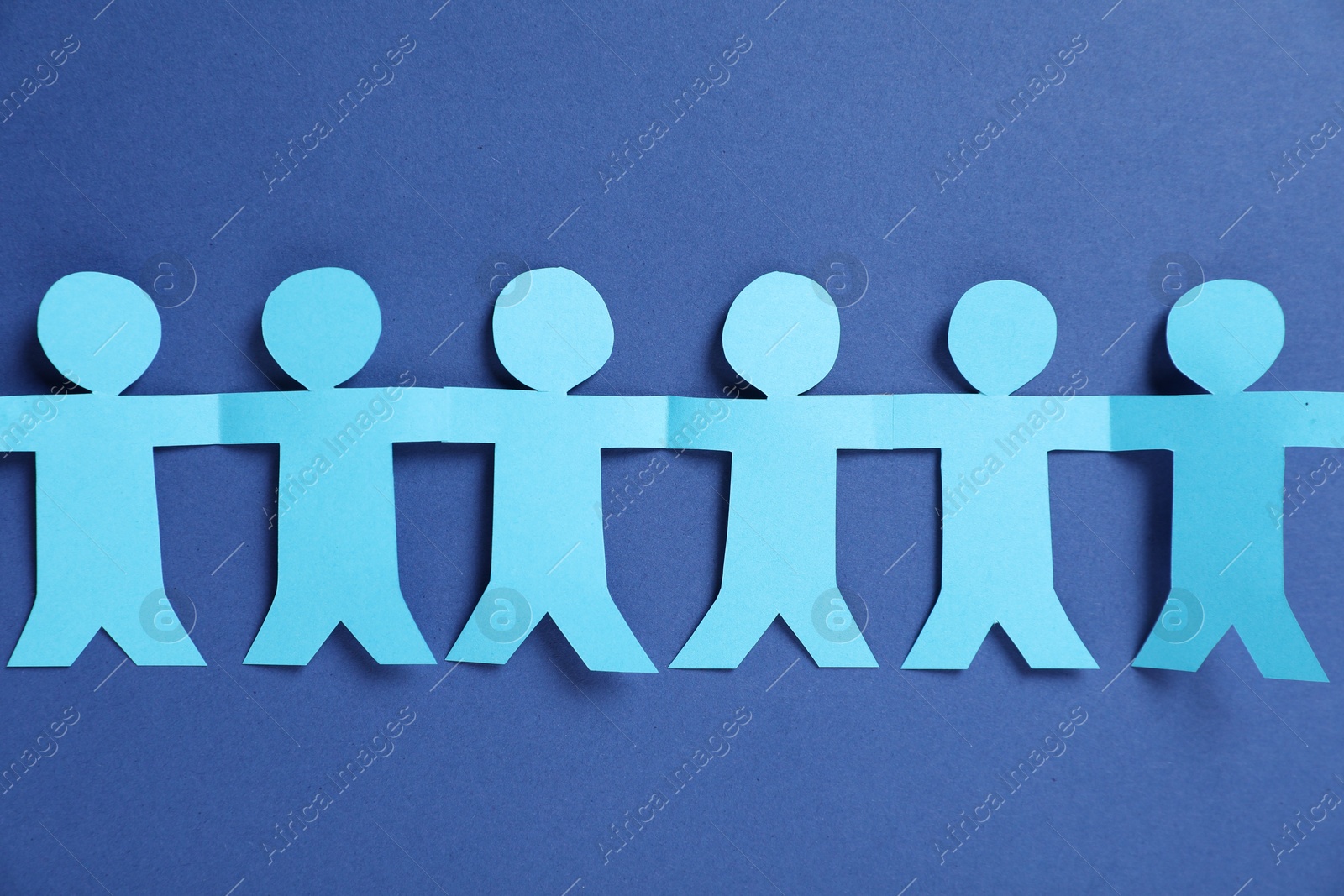 Photo of Human paper figures holding hands on blue background, flat lay