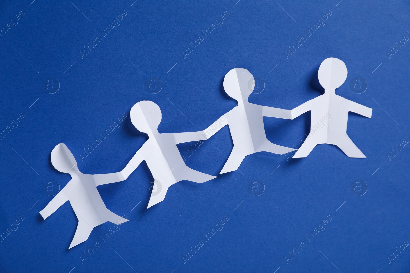 Human paper figures holding hands on blue background, flat lay Photo of Human paper figures holding hands on blue background, flat lay