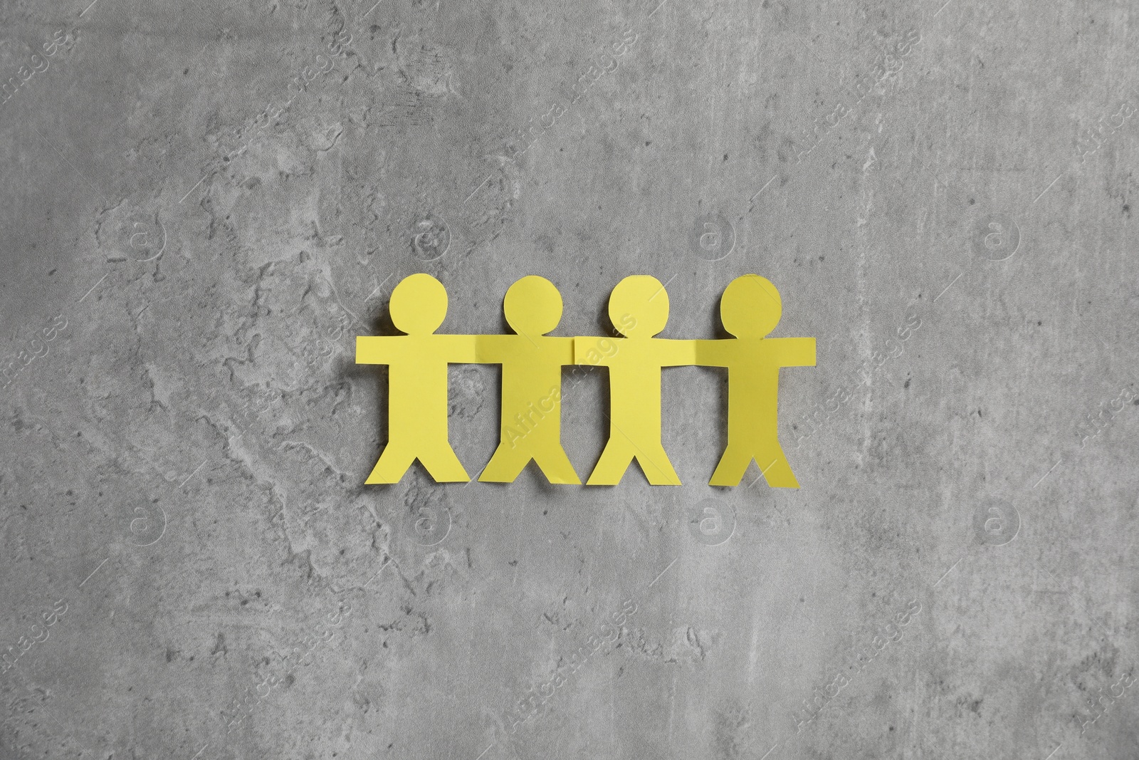Photo of Human paper figures holding hands on grey background, flat lay