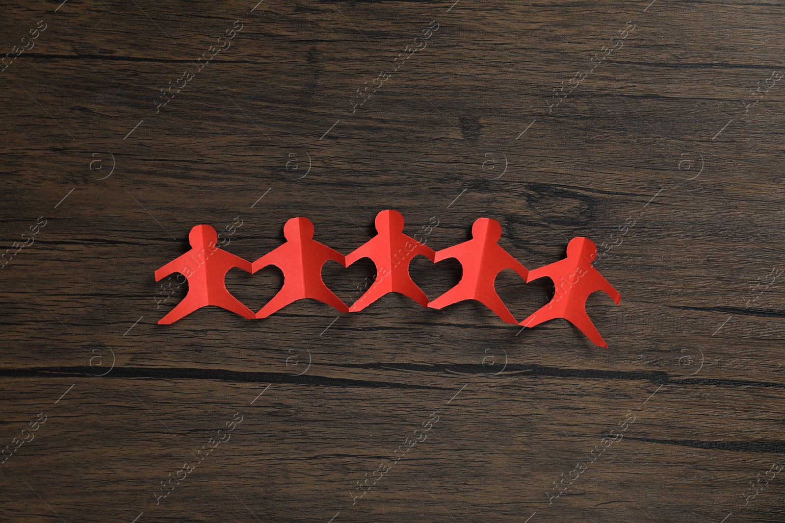 Human paper figures holding hands on wooden background, flat lay Photo of Human paper figures holding hands on wooden background, flat lay