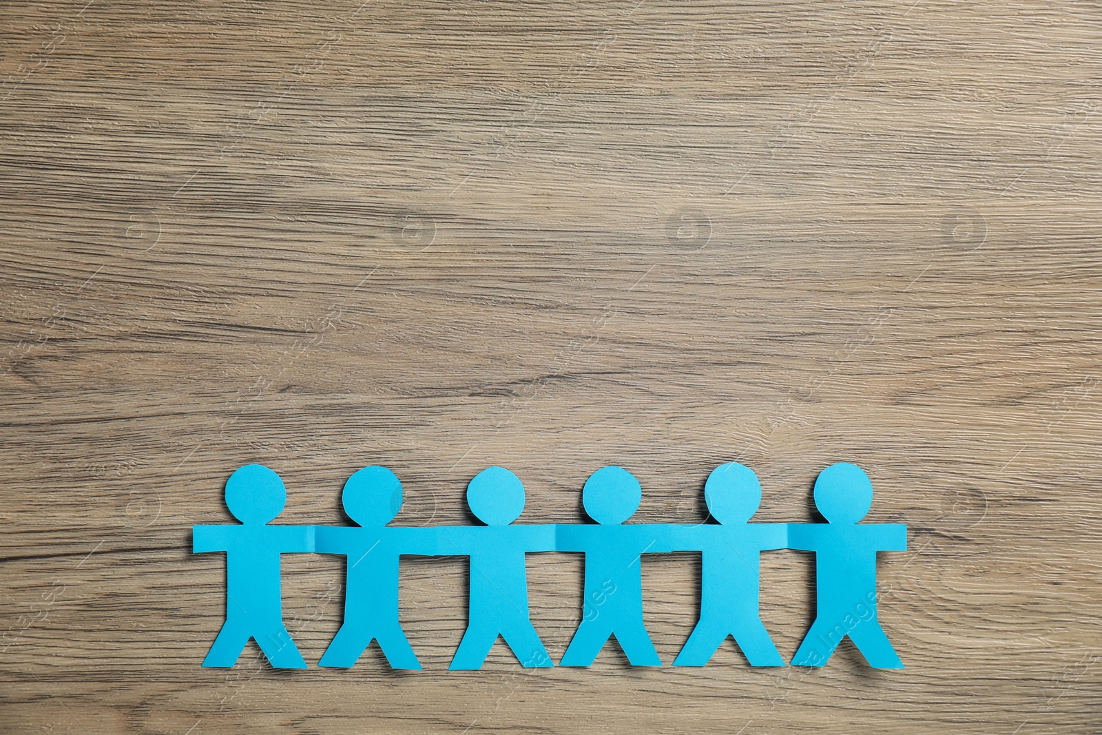 Human paper figures holding hands on wooden background, flat lay Photo of Human paper figures holding hands on wooden background, flat lay