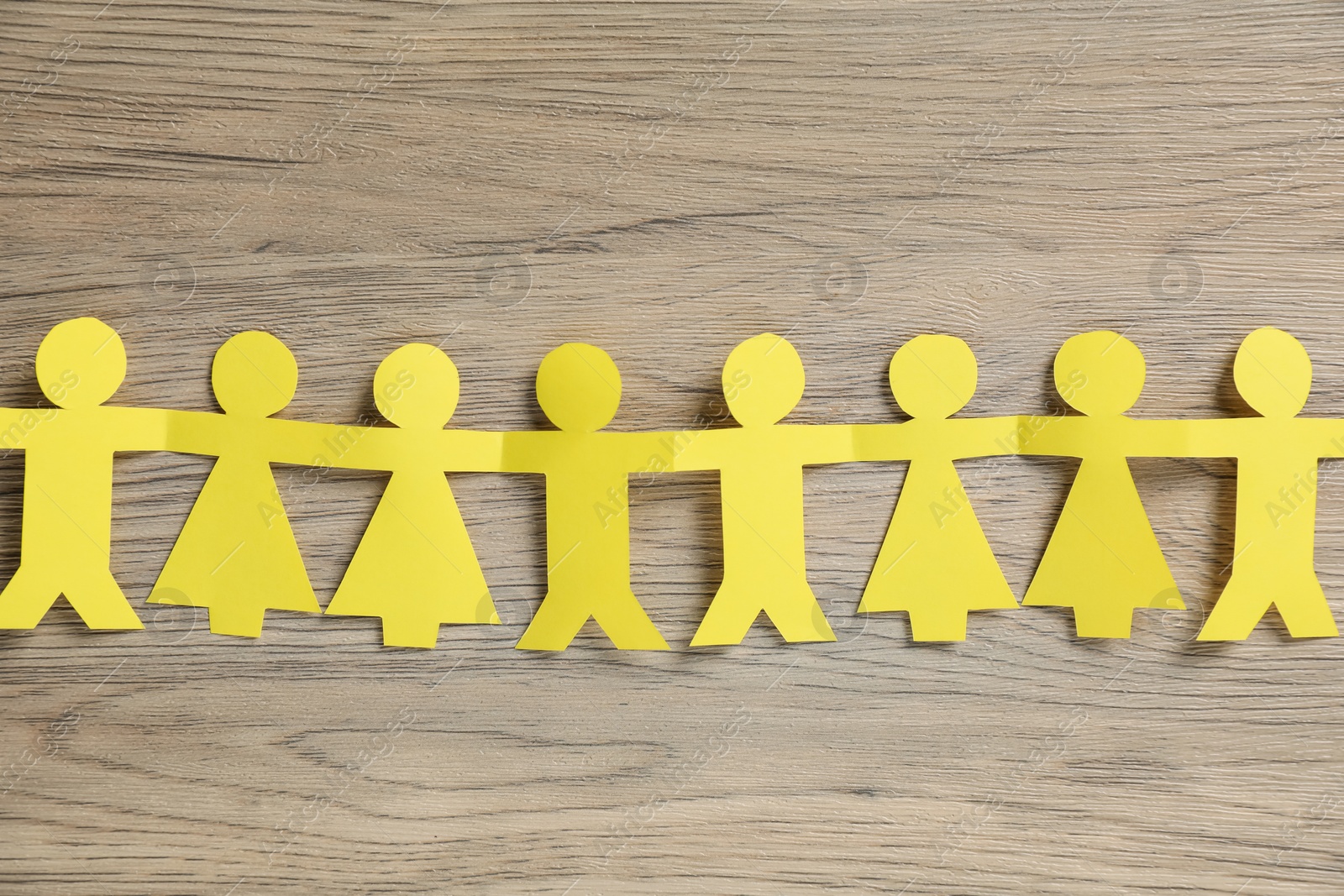 Photo of Human paper figures holding hands on wooden background, flat lay