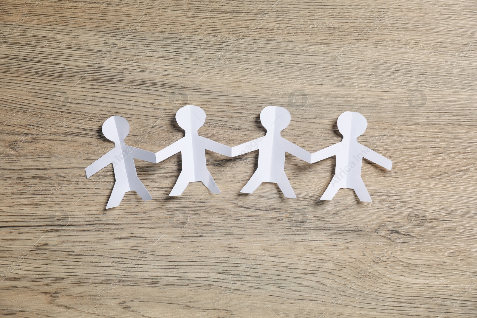 Human paper figures holding hands on wooden background, flat lay Photo of Human paper figures holding hands on wooden background, flat lay