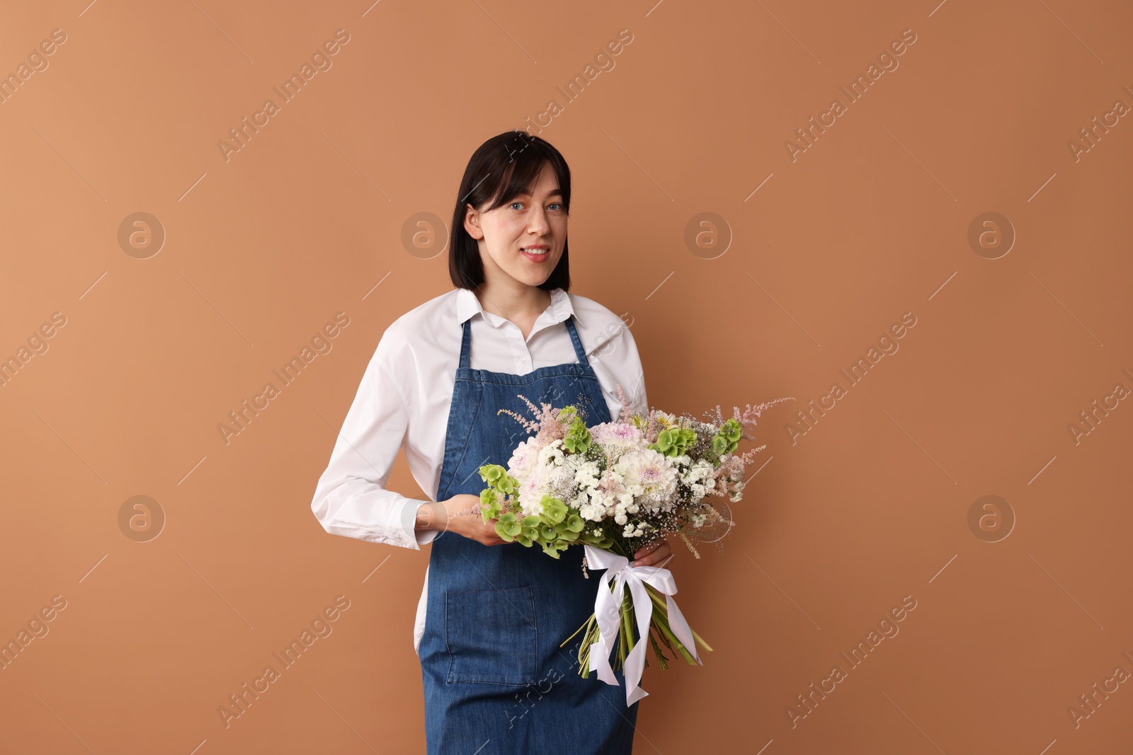 Florist with beautiful bouquet of flowers on dark beige background Photo of Florist with beautiful bouquet of flowers on dark beige background