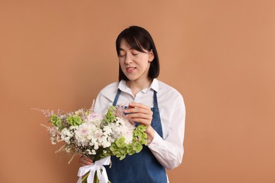 Photo of Florist with beautiful bouquet of flowers on dark beige background