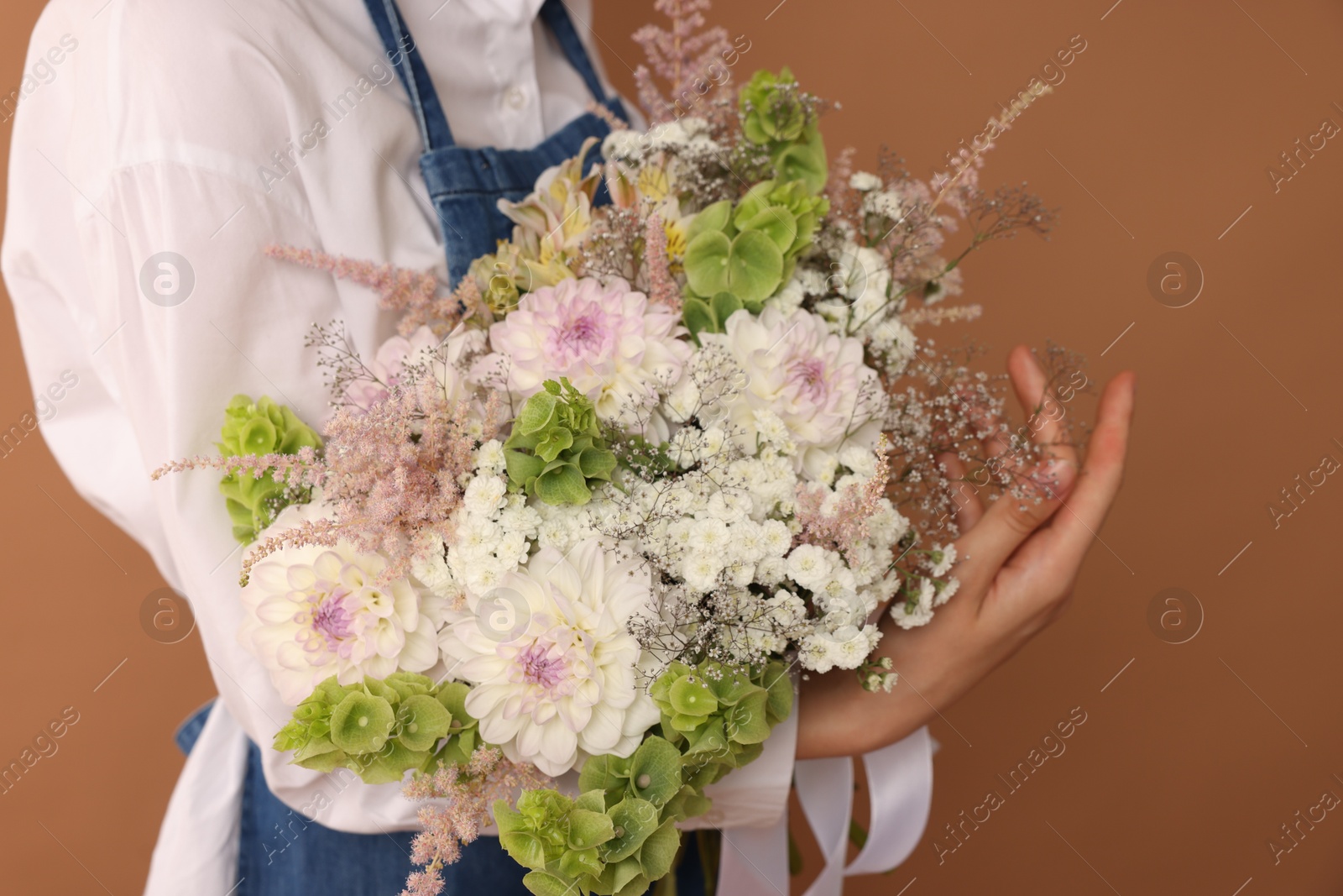 Florist with beautiful bouquet of flowers on dark beige background, closeup Photo of Florist with beautiful bouquet of flowers on dark beige background, closeup