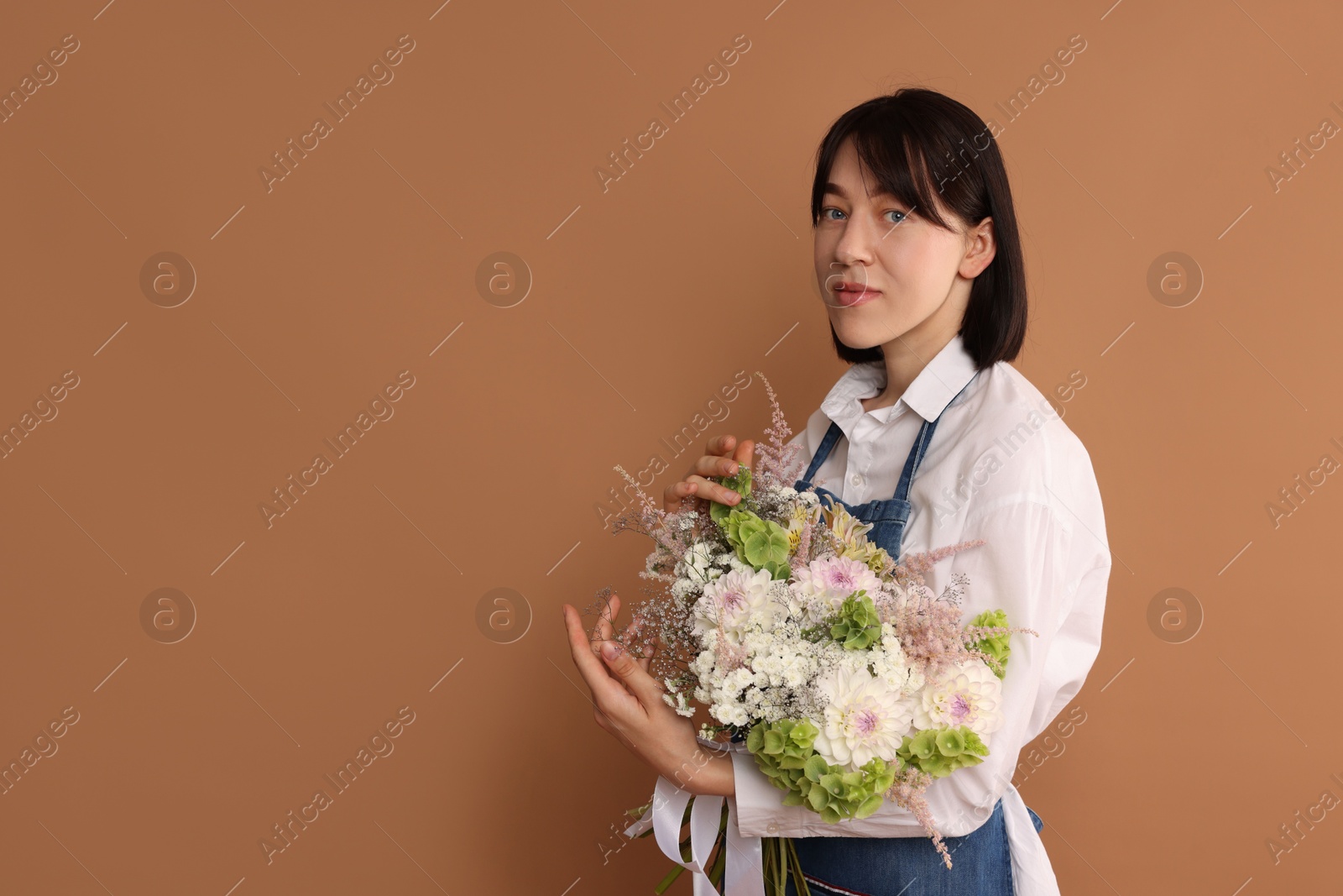 Florist with beautiful bouquet of flowers on dark beige background, space for text Photo of Florist with beautiful bouquet of flowers on dark beige background, space for text