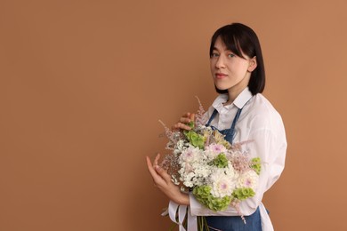 Photo of Florist with beautiful bouquet of flowers on dark beige background, space for text