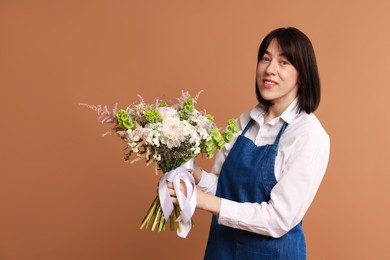 Photo of Florist with beautiful bouquet of flowers on dark beige background