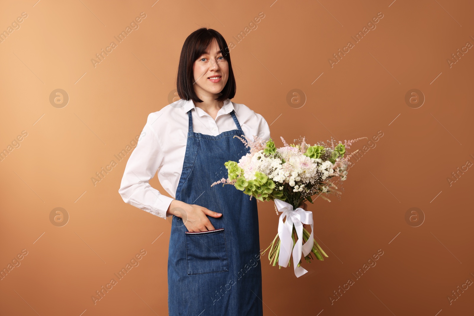 Florist with beautiful bouquet of flowers on dark beige background Photo of Florist with beautiful bouquet of flowers on dark beige background