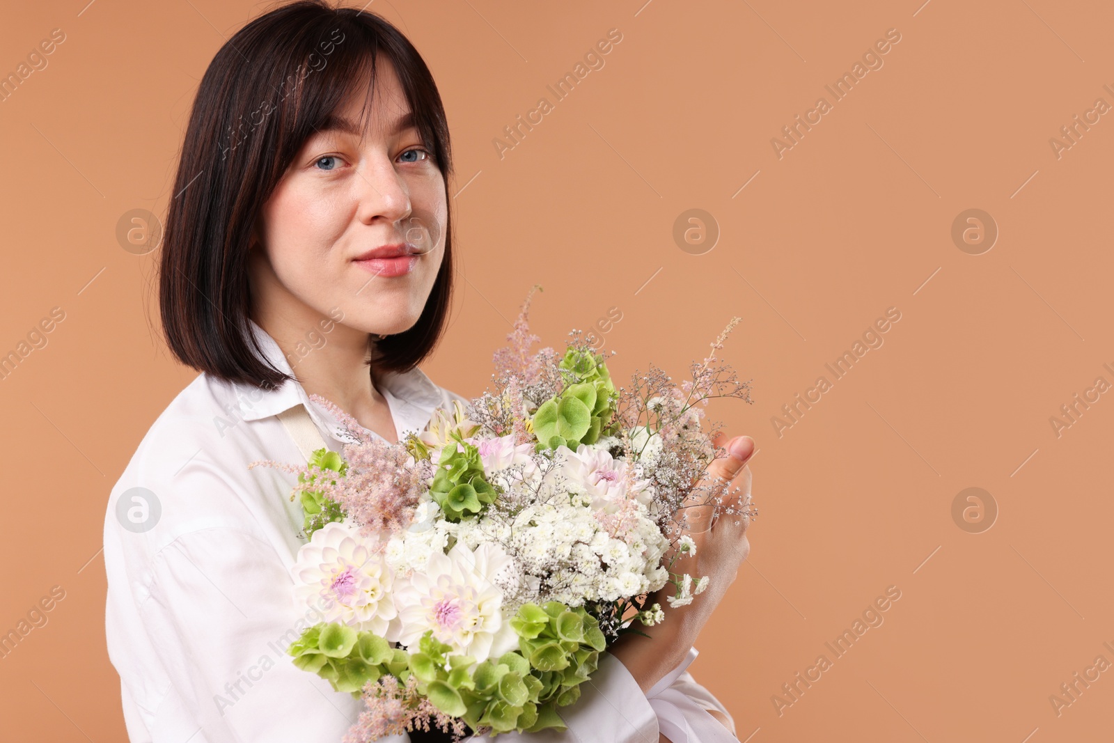 Florist with beautiful bouquet of flowers on beige background, space for text Photo of Florist with beautiful bouquet of flowers on beige background, space for text