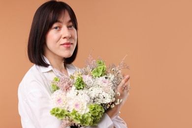 Photo of Florist with beautiful bouquet of flowers on beige background, space for text