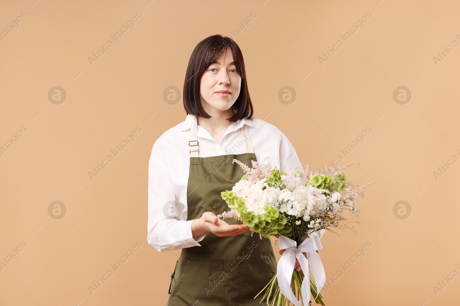 Florist with beautiful bouquet of flowers on beige background Photo of Florist with beautiful bouquet of flowers on beige background
