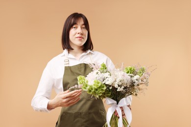Photo of Florist with beautiful bouquet of flowers on beige background