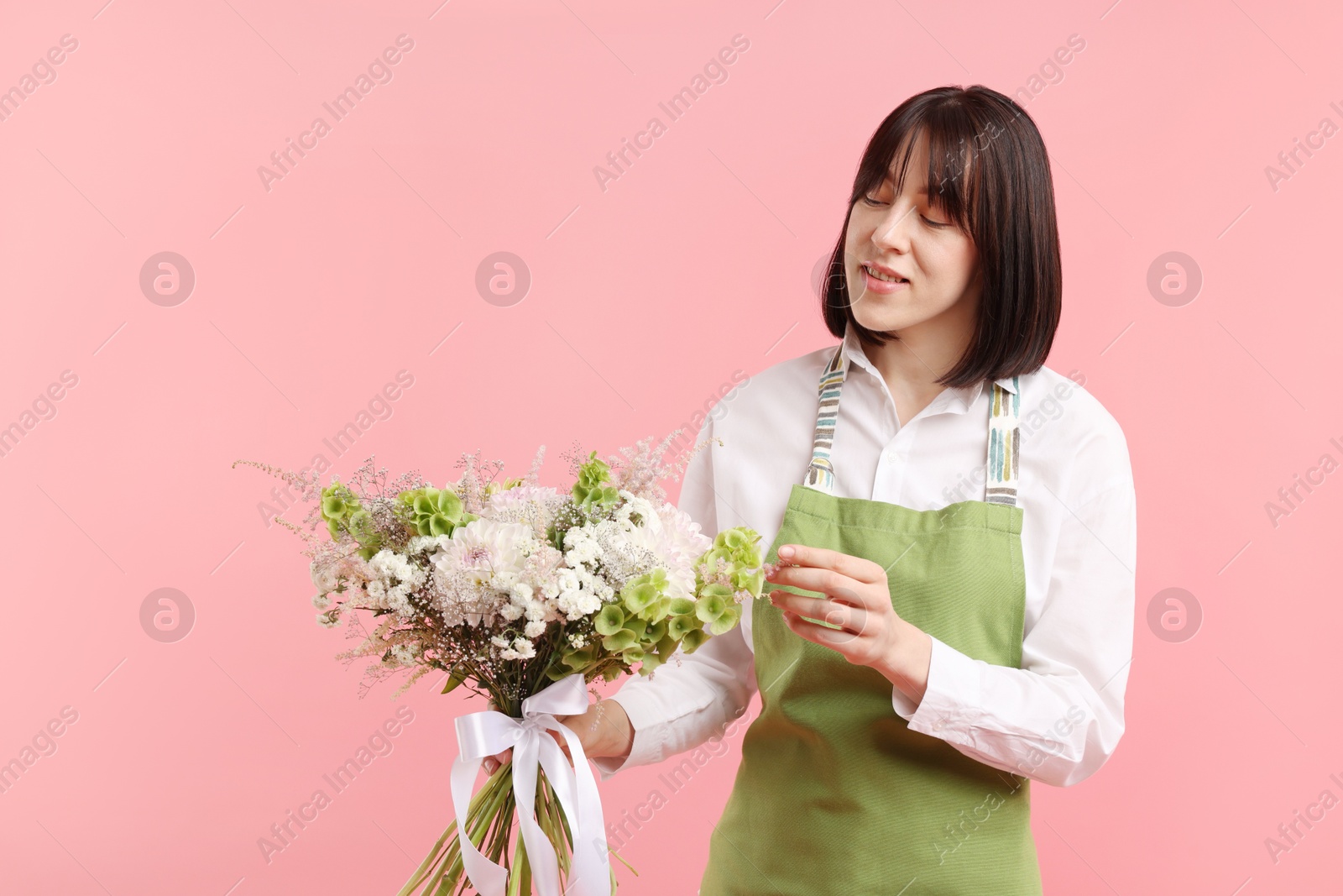 Florist with beautiful bouquet of flowers on pink background Photo of Florist with beautiful bouquet of flowers on pink background