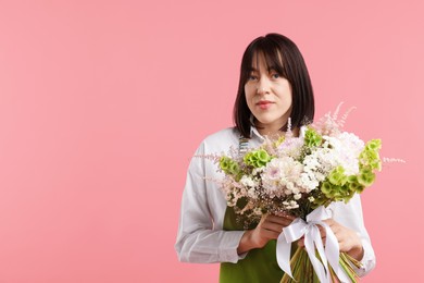 Photo of Florist with beautiful bouquet of flowers on pink background, space for text