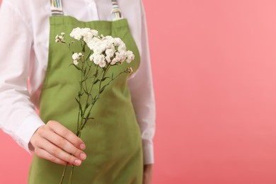 Photo of Florist with beautiful flowers on pink background, closeup. Space for text
