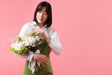 Photo of Florist with beautiful bouquet of flowers on pink background, space for text