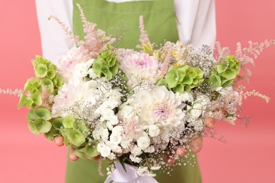 Photo of Florist with beautiful bouquet of flowers on pink background, closeup