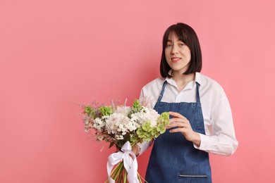 Photo of Florist with beautiful bouquet of flowers on pink background, space for text