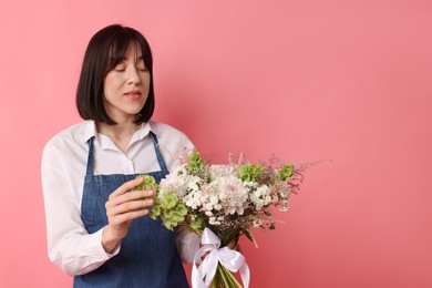 Photo of Florist with beautiful bouquet of flowers on pink background, space for text